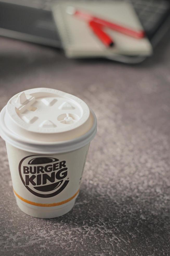 Washington, USA - January 18 2023  Coffee Cup Mug Burger King with notebook and laptop on gray table In studio lighting, Burger King is a popular food in America. photo