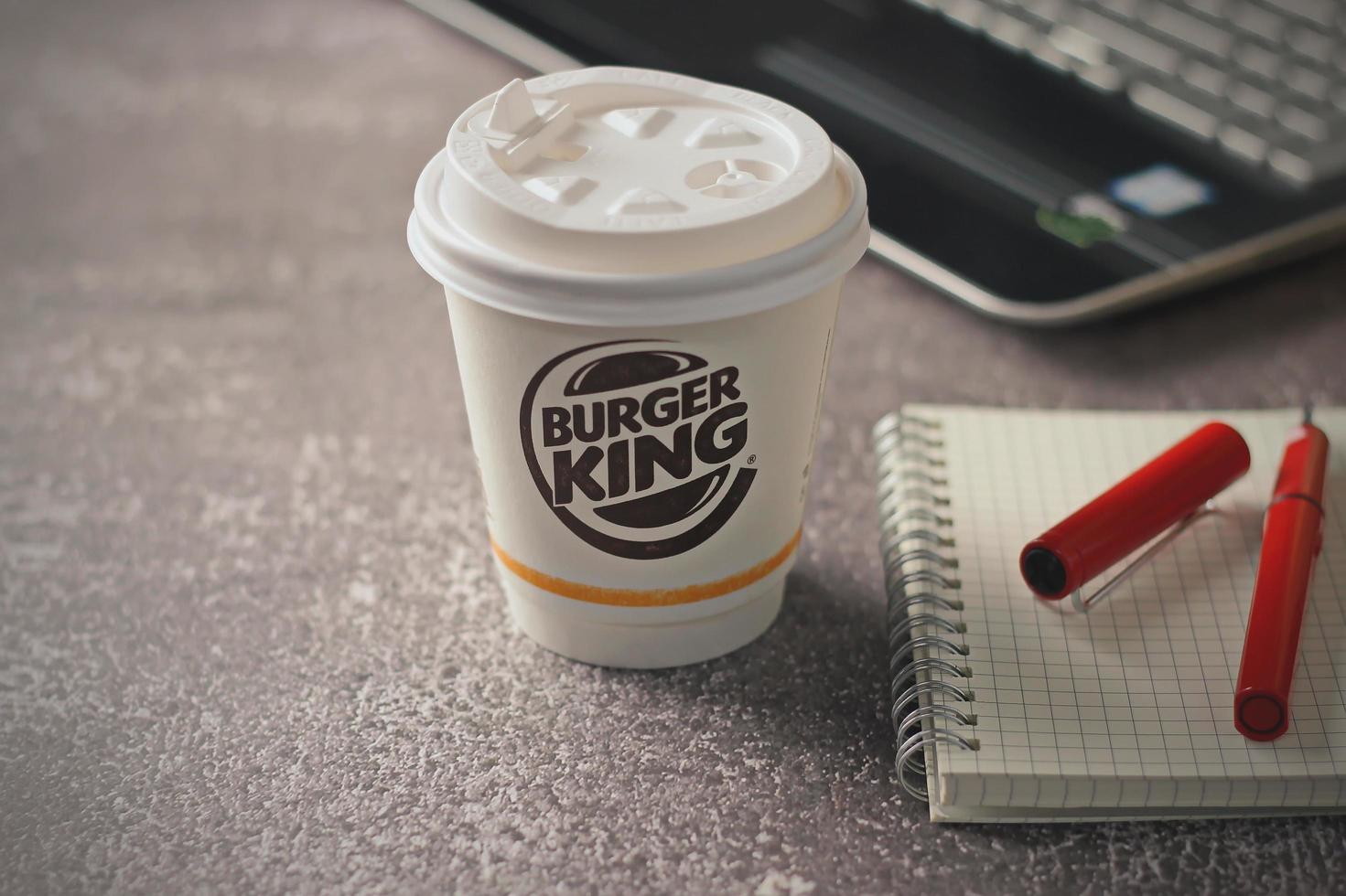 Washington, USA - January 18 2023  Coffee Cup Mug Burger King with notebook and laptop on gray table In studio lighting, Burger King is a popular food in America. photo