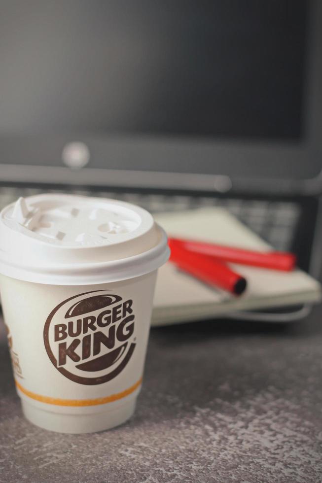 Washington, USA - January 18 2023  Coffee Cup Mug Burger King with notebook and laptop on gray table In studio lighting, Burger King is a popular food in America. photo