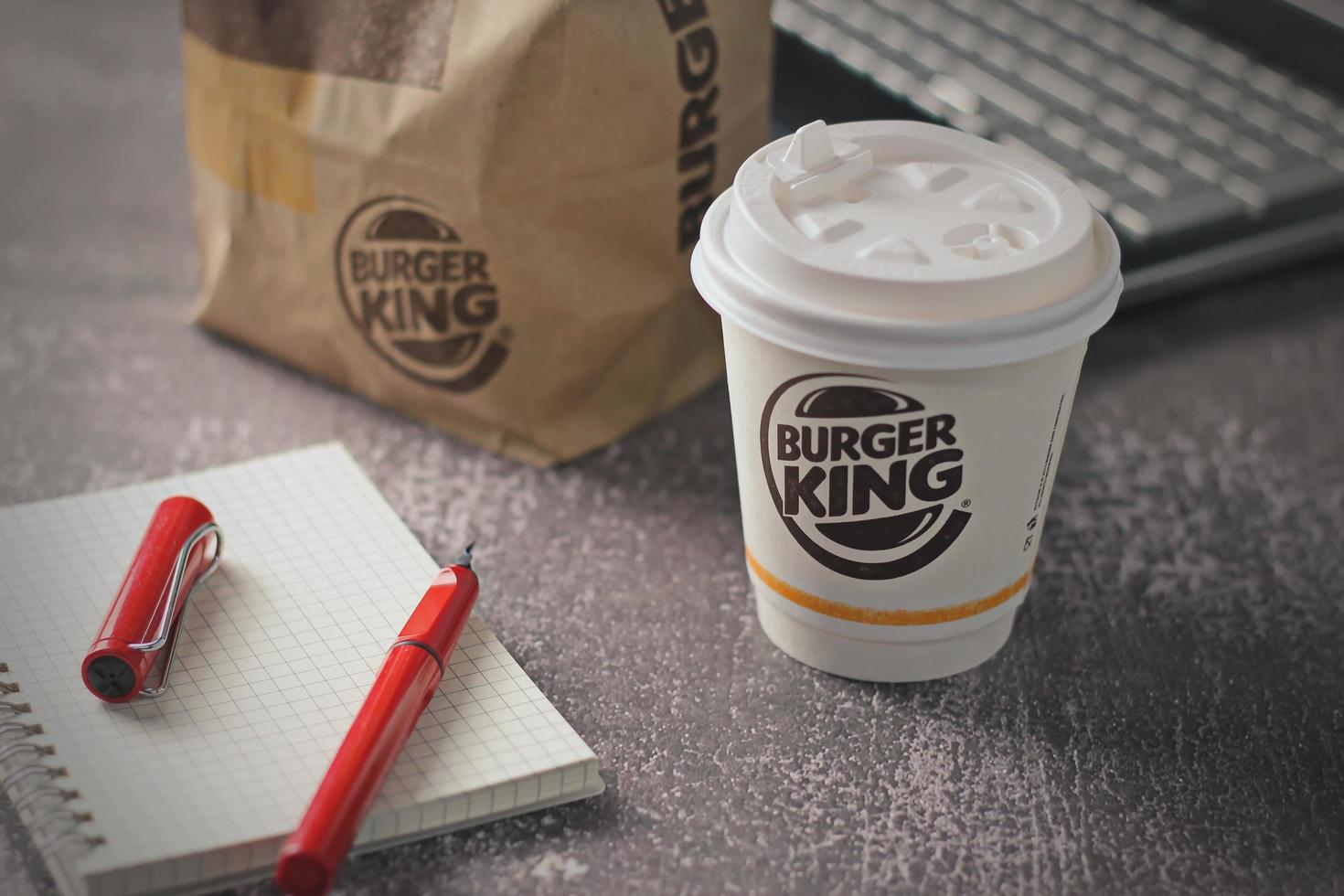 Washington, USA - January 18 2023  Coffee Cup Mug Burger King with notebook and laptop on gray table In studio lighting, Burger King is a popular food in America. photo