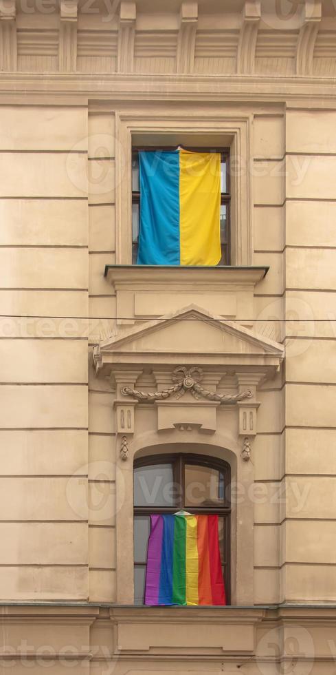 Pride of LGBT rainbow flag and flag of Ukraine in the city of Bratislava. View of the windows of the building with rainbow and blue-and-yellow flags. photo
