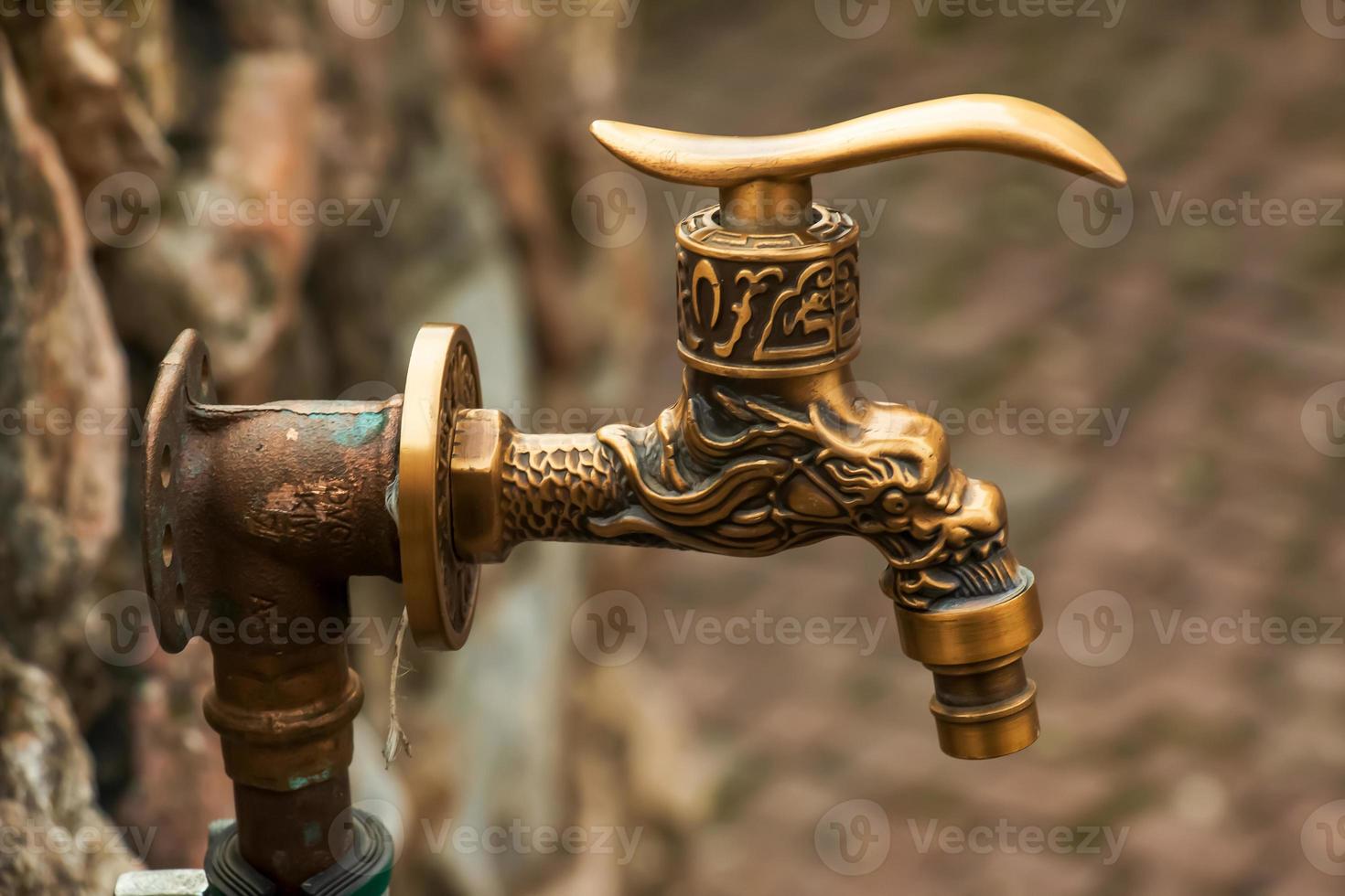 Antique brass water faucet as an architectural monument. Old tap with water on the street. photo