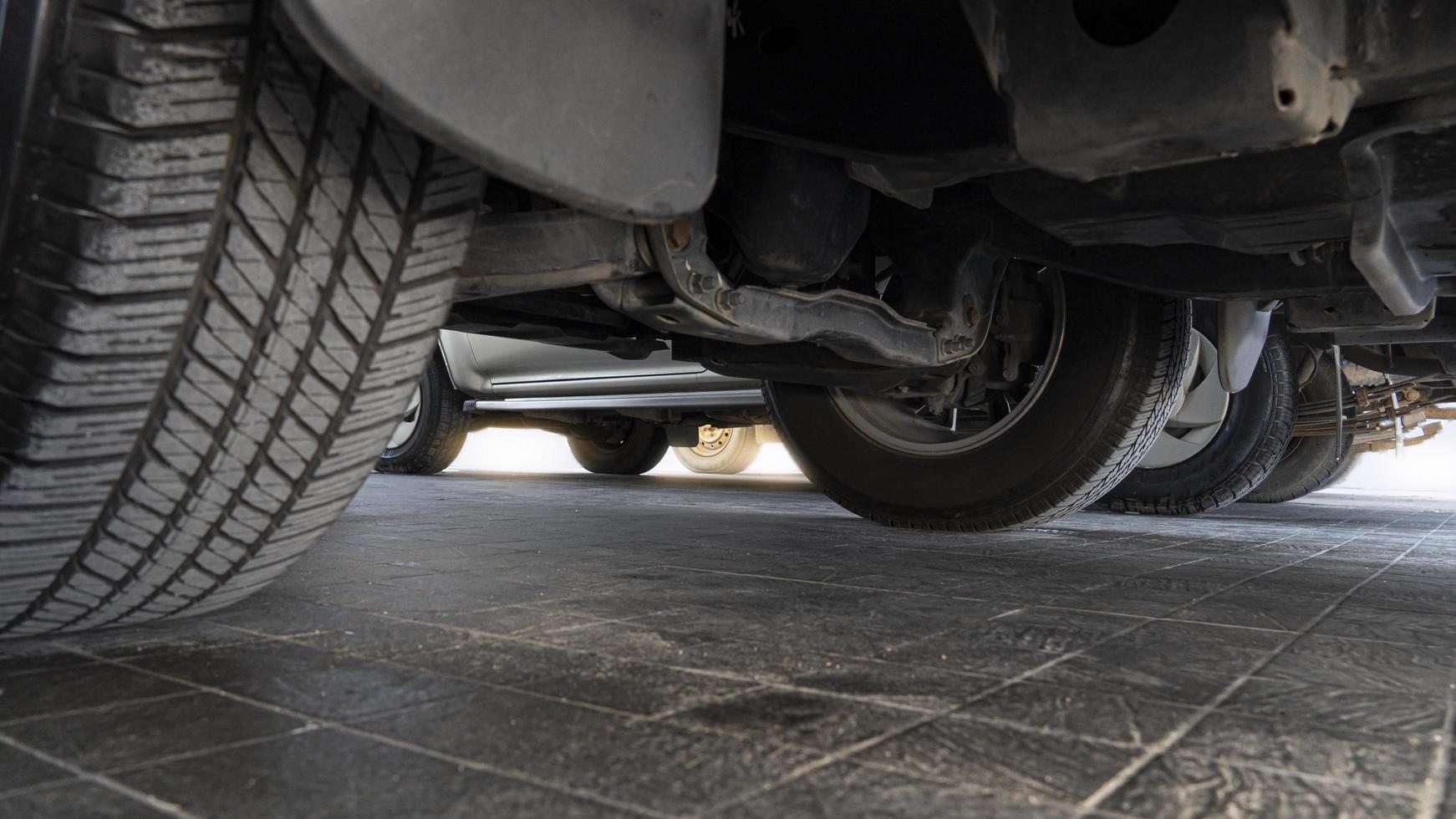 Abstract under view of undercarriage of the cars in the parking area. on black tile floor. photo