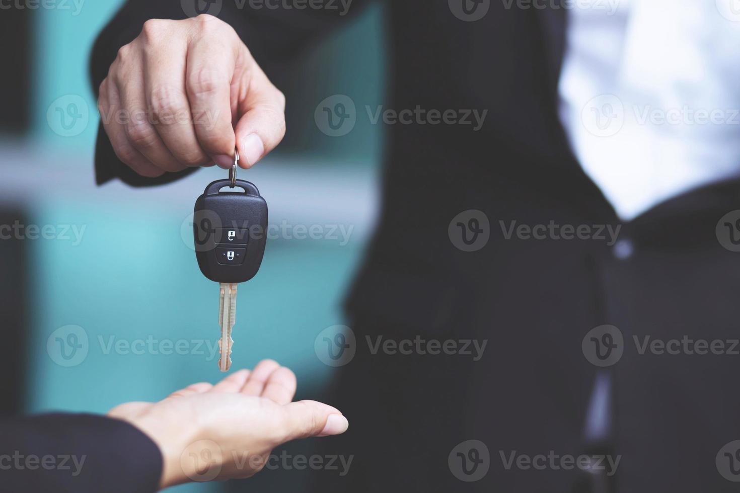 The car salesman is handing over the keys to the buyer after the lease has been agreed. photo