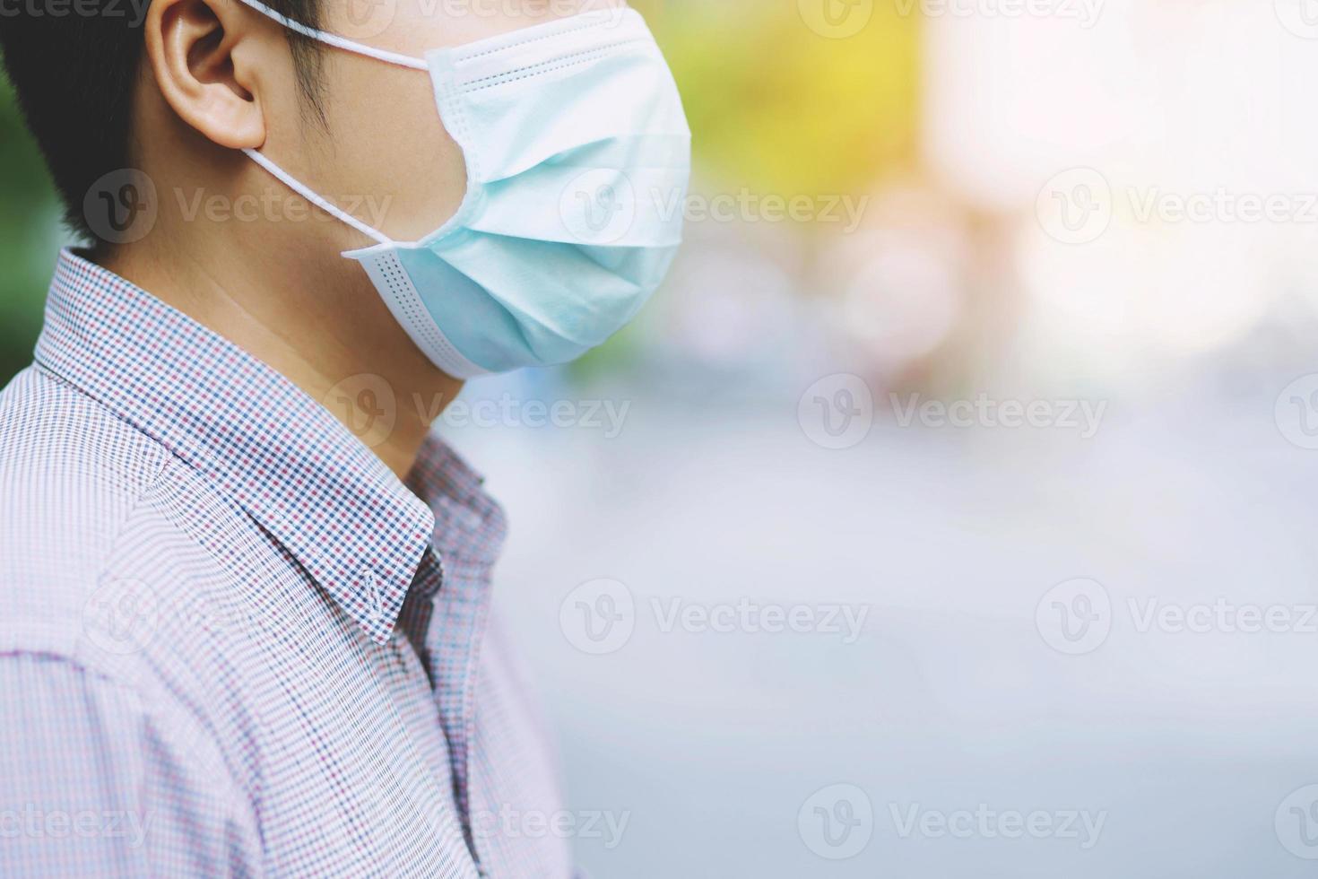 portrait of brunette man in a surgical bandage on a background of a modern building, coronavirus, illness, infection, quarantine, medical mask photo