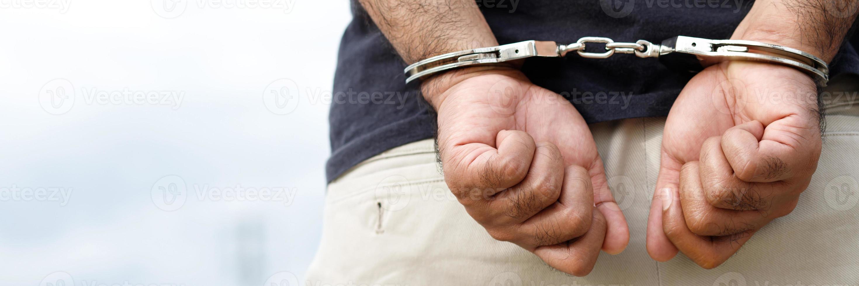 Prisoner male criminal standing in handcuffs with hands behind back. photo