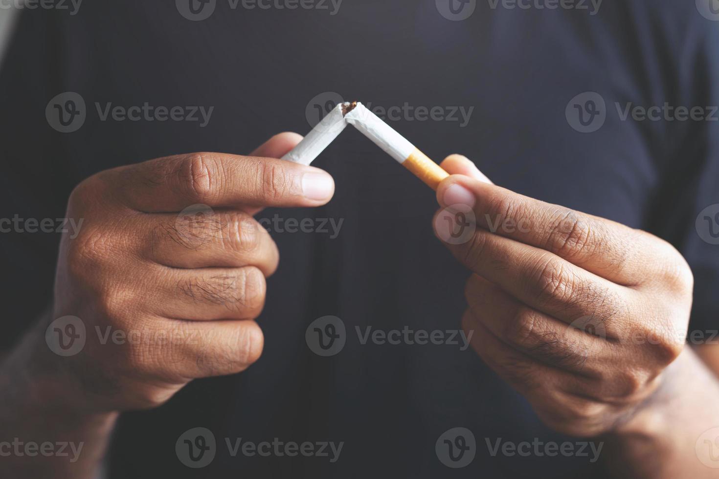 Stop smoking cigarettes concept. Portrait of beautiful smiling girl holding broken cigarette in hands. photo