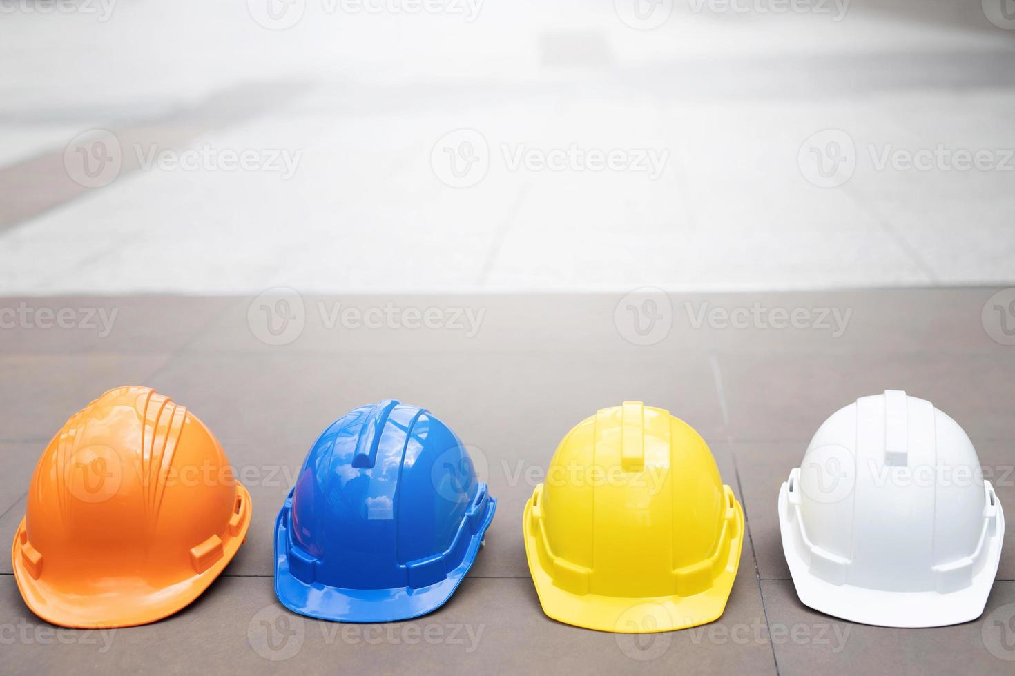 white, yellow and blue hard safety helmet hat for safety project of workman as engineer or worker, on concrete floor on city. photo