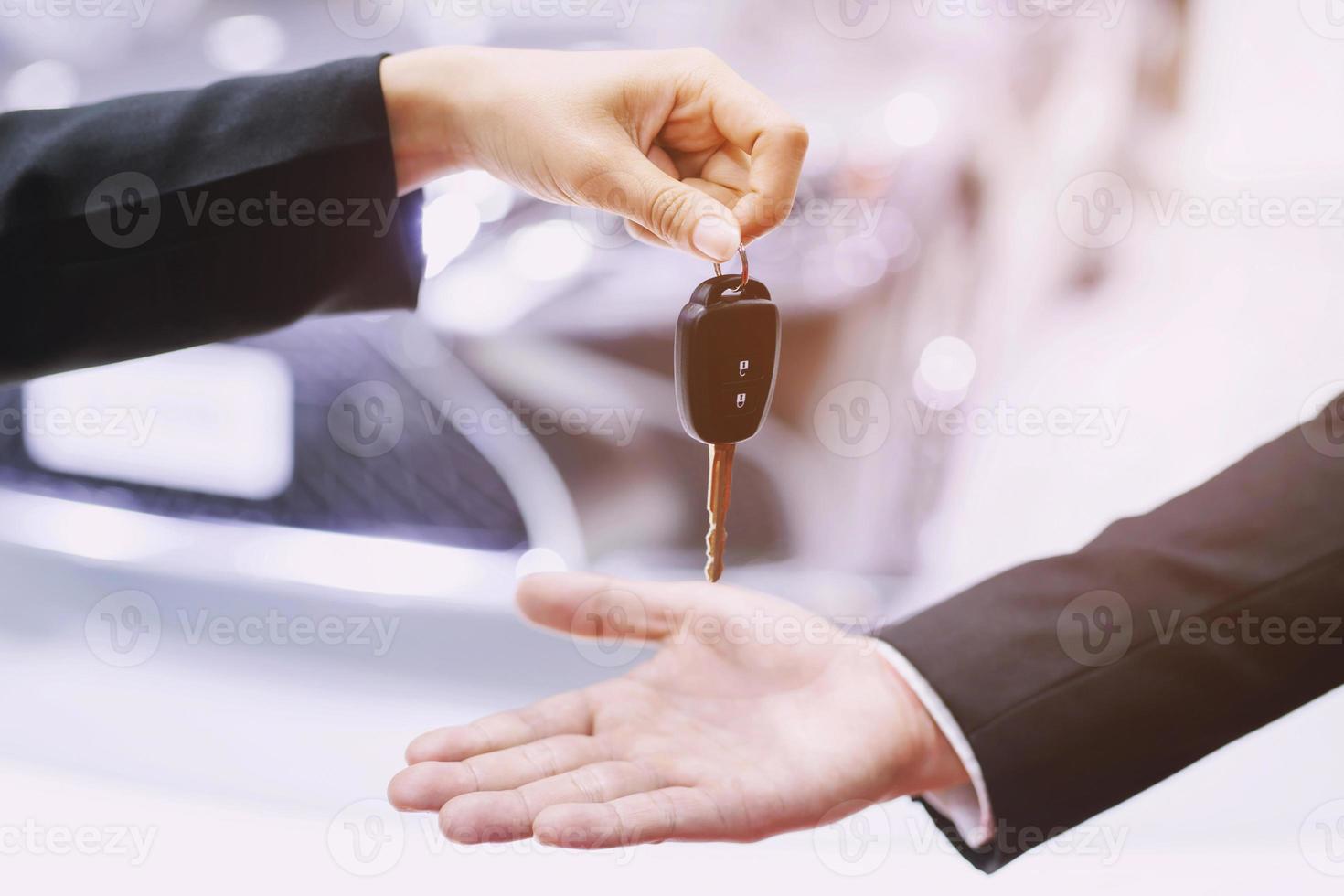 The car salesman is handing over the keys to the buyer after the lease has been agreed. photo