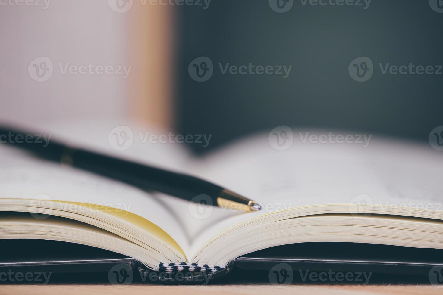 Education learning concept with opening book or textbook in old library, stack piles of literature text academic archive on reading desk and aisle of bookshelves in school study class room photo