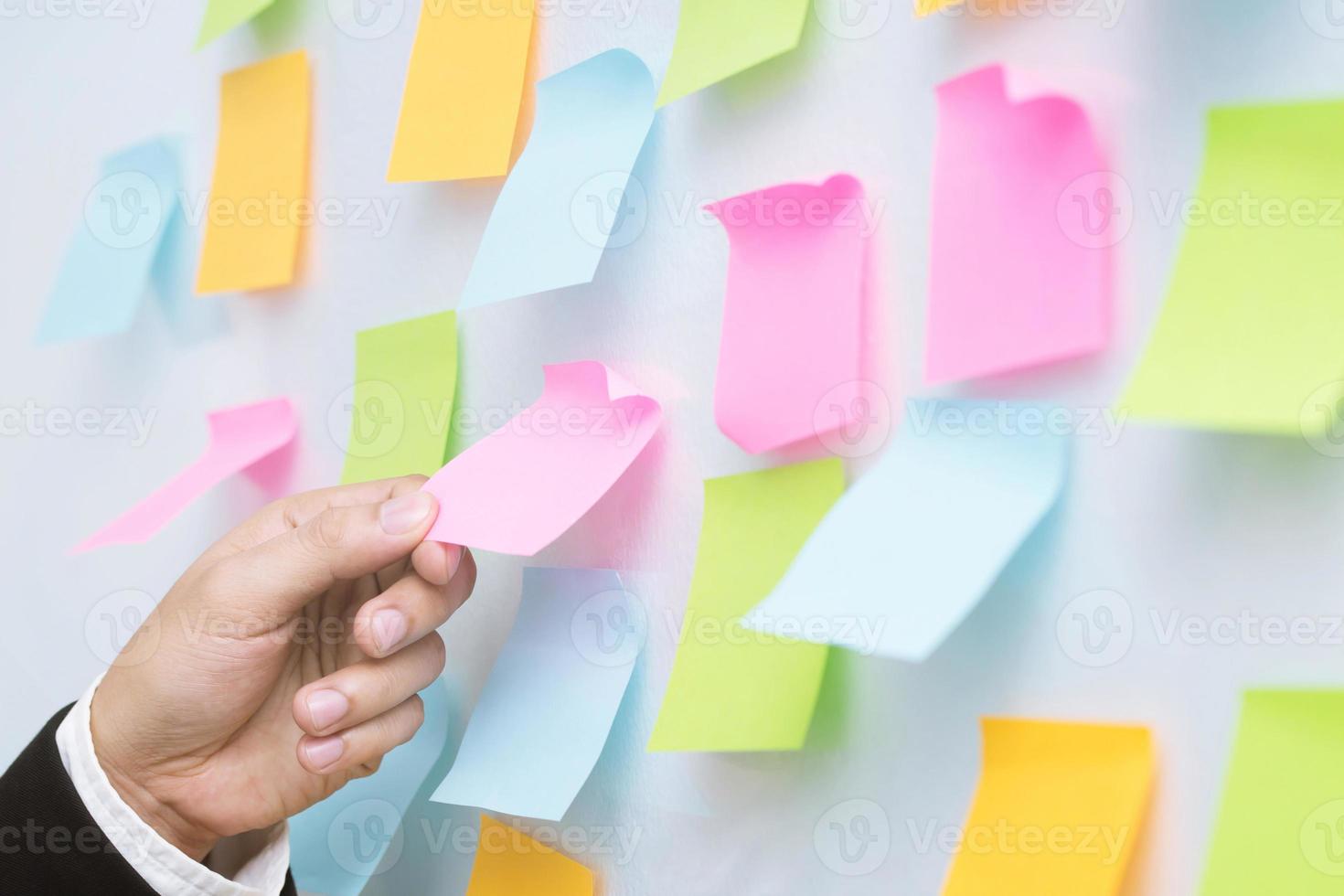 male employee write on colorful sticky notes develop business project in office, concentrated biracial man worker brainstorm engaged in creative thinking make startup plan photo