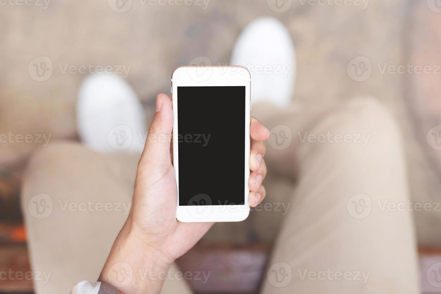 Young man wear plaid shirt.  close up hand using on cell phone during rest on sofa. sitting in watching message on mobile smart phone during break relax. photo