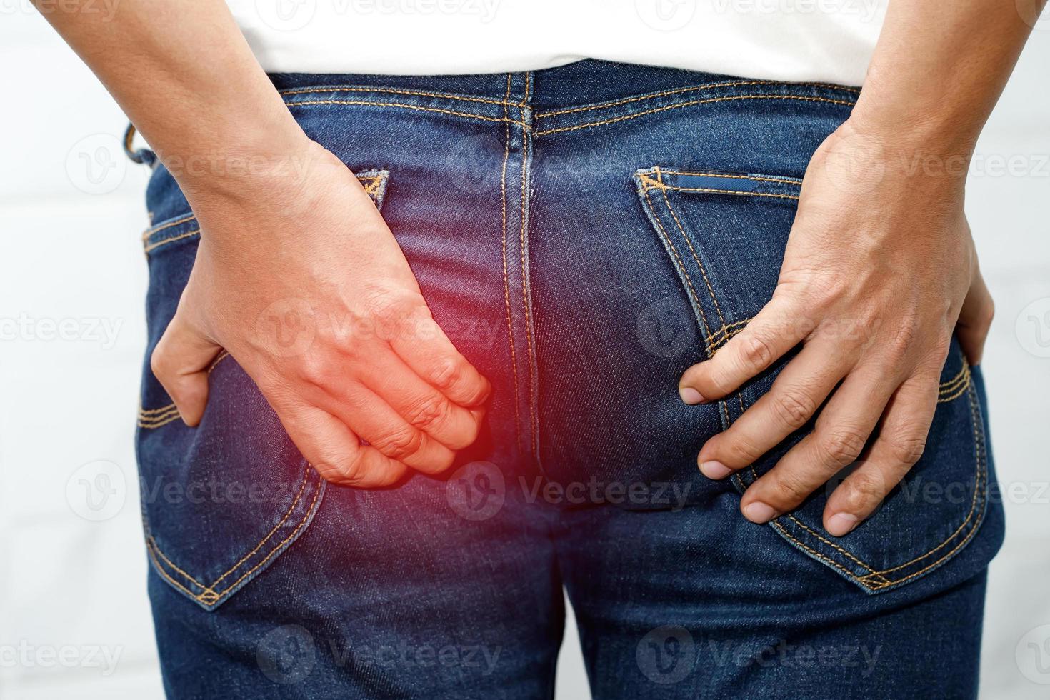 Man with hemorrhoids holding his butt in pain because having abdominal constipation photo