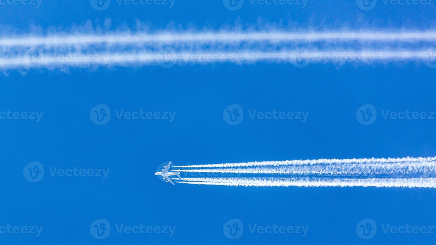Four engined airplane during flight in high altitude with condensation trails photo