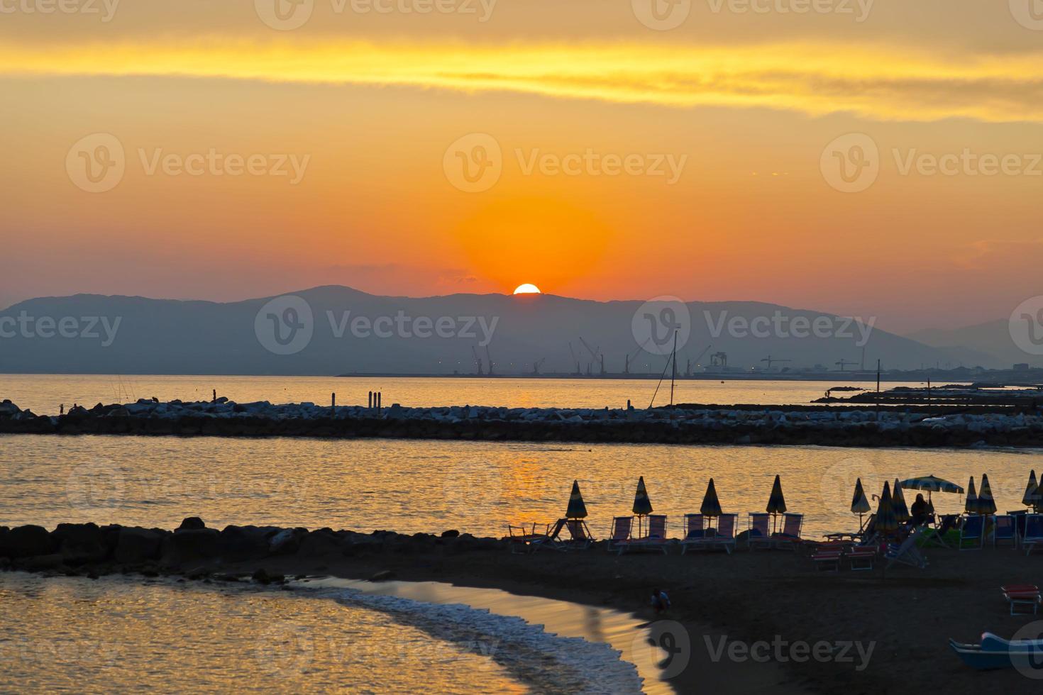 puesta de sol sobre el mar con playa desierta en Italia foto