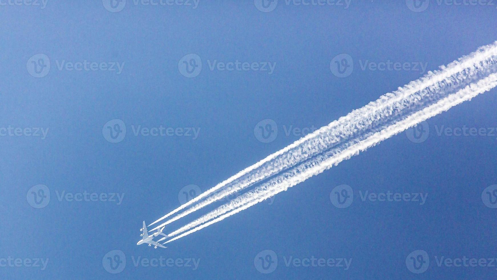 Four engined airplane during flight in high altitude with condensation trails photo