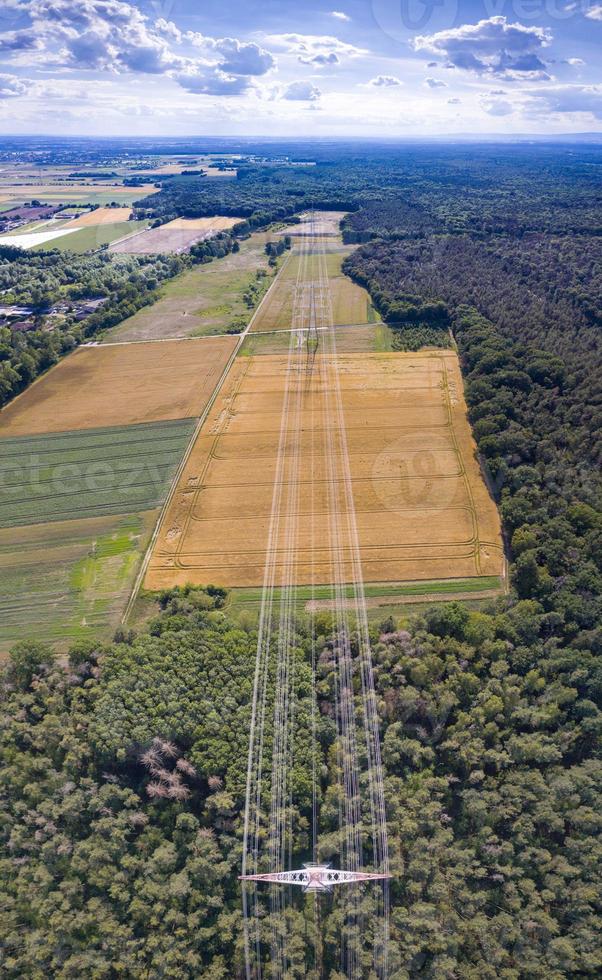 Aerial view along a power line in forest area with metal power poles and high voltage wires photo