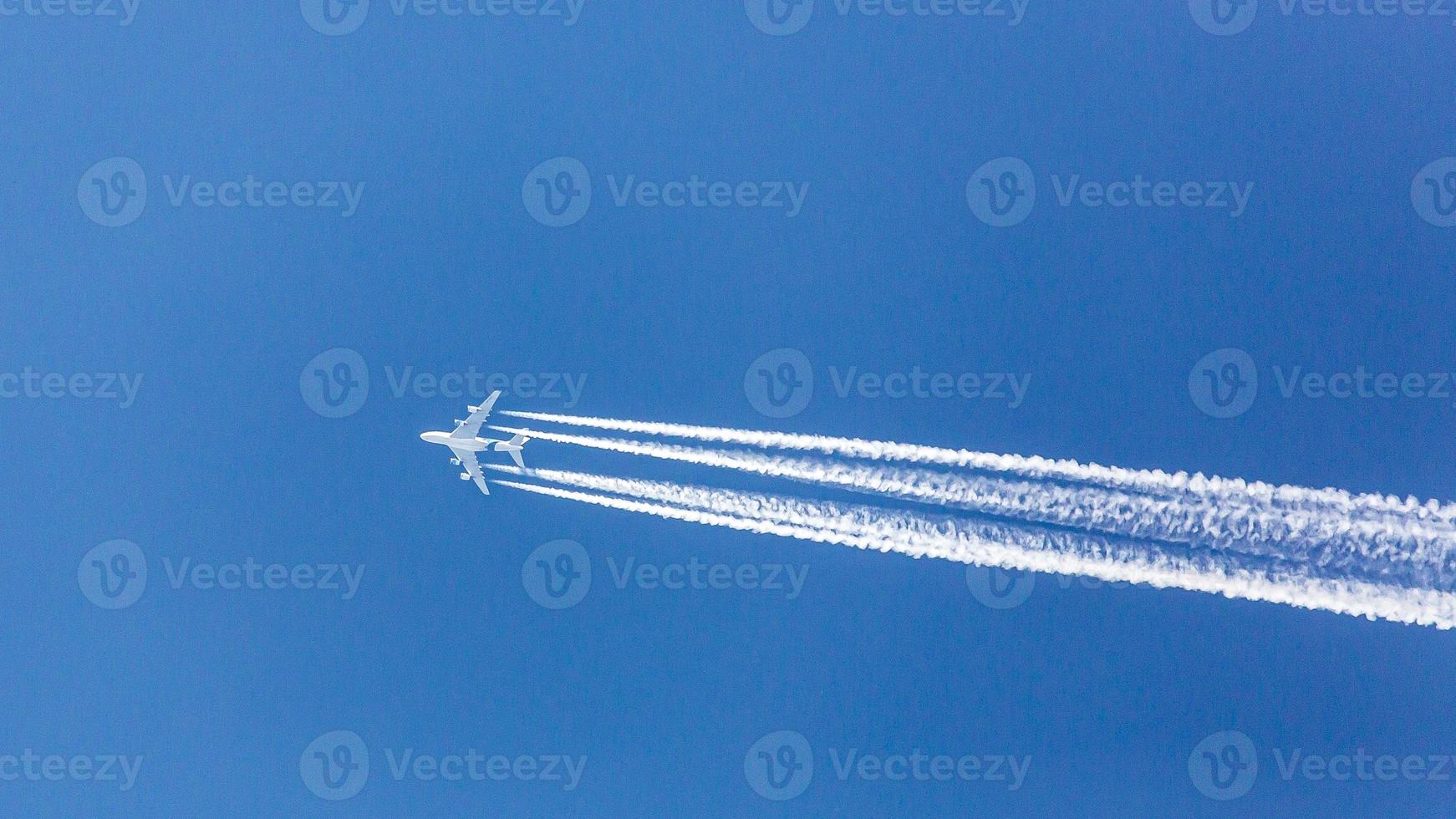Four engined airplane during flight in high altitude with condensation trails photo