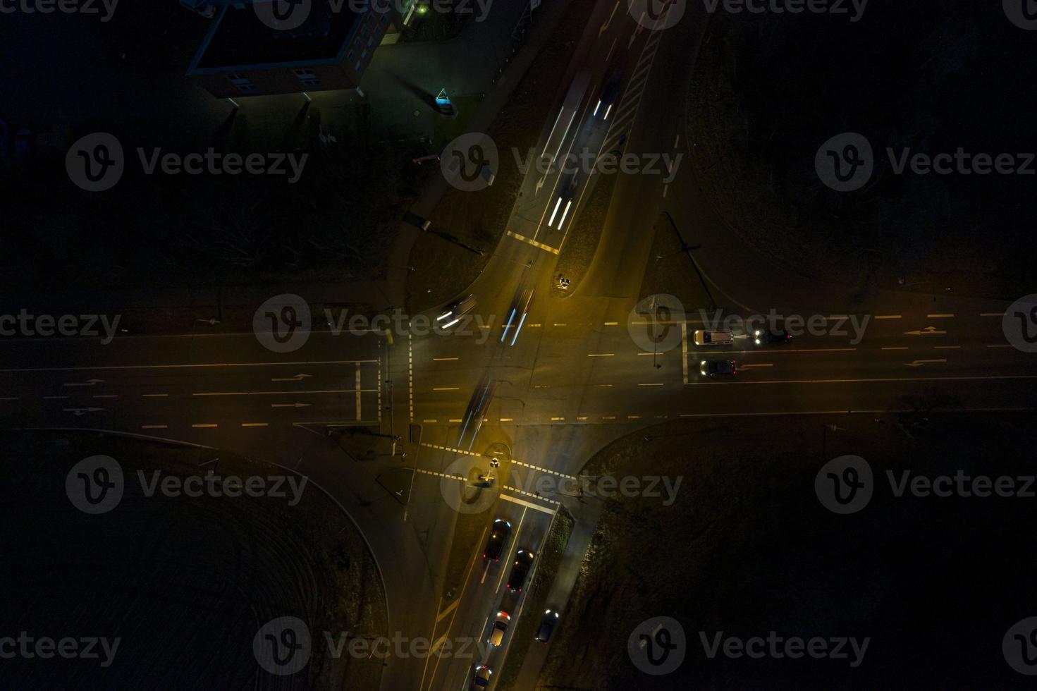 Vertical drone shot of a lighted street intersection at night with traffic photo