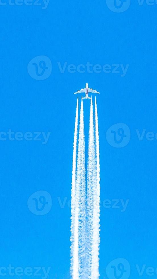 Four engined airplane during flight in high altitude with condensation trails photo
