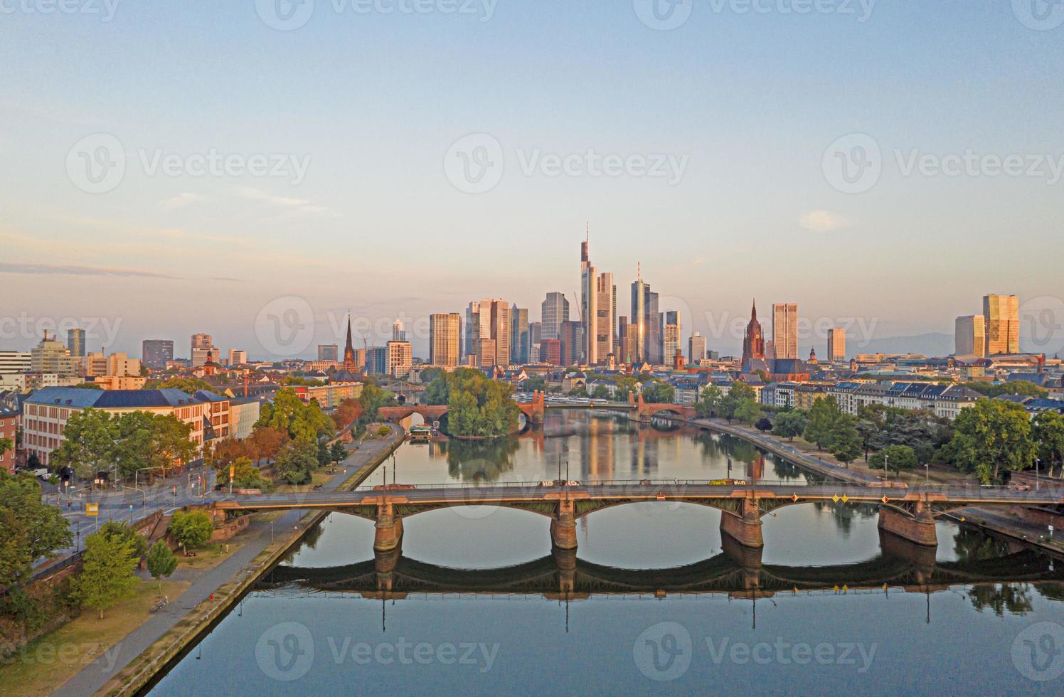 imagen aérea del horizonte de frankfurt y el río principal durante el amanecer con reflejos en el agua y las fachadas de vidrio de los rascacielos foto