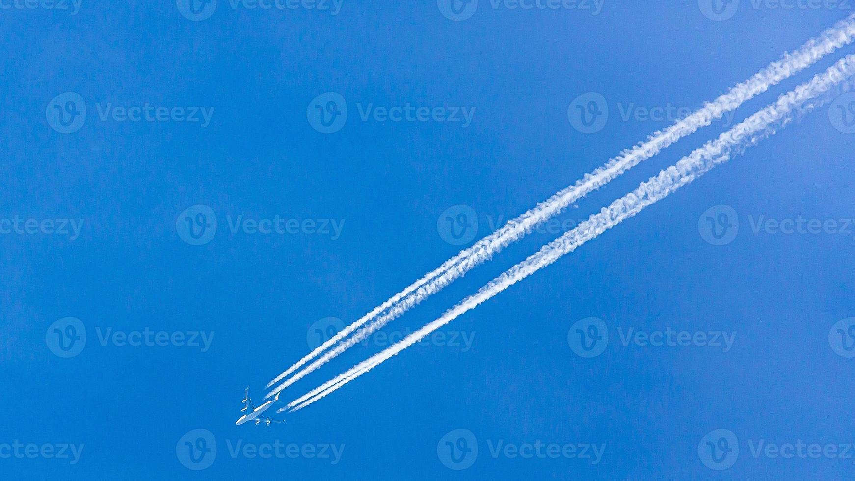 Four engined airplane during flight in high altitude with condensation trails photo