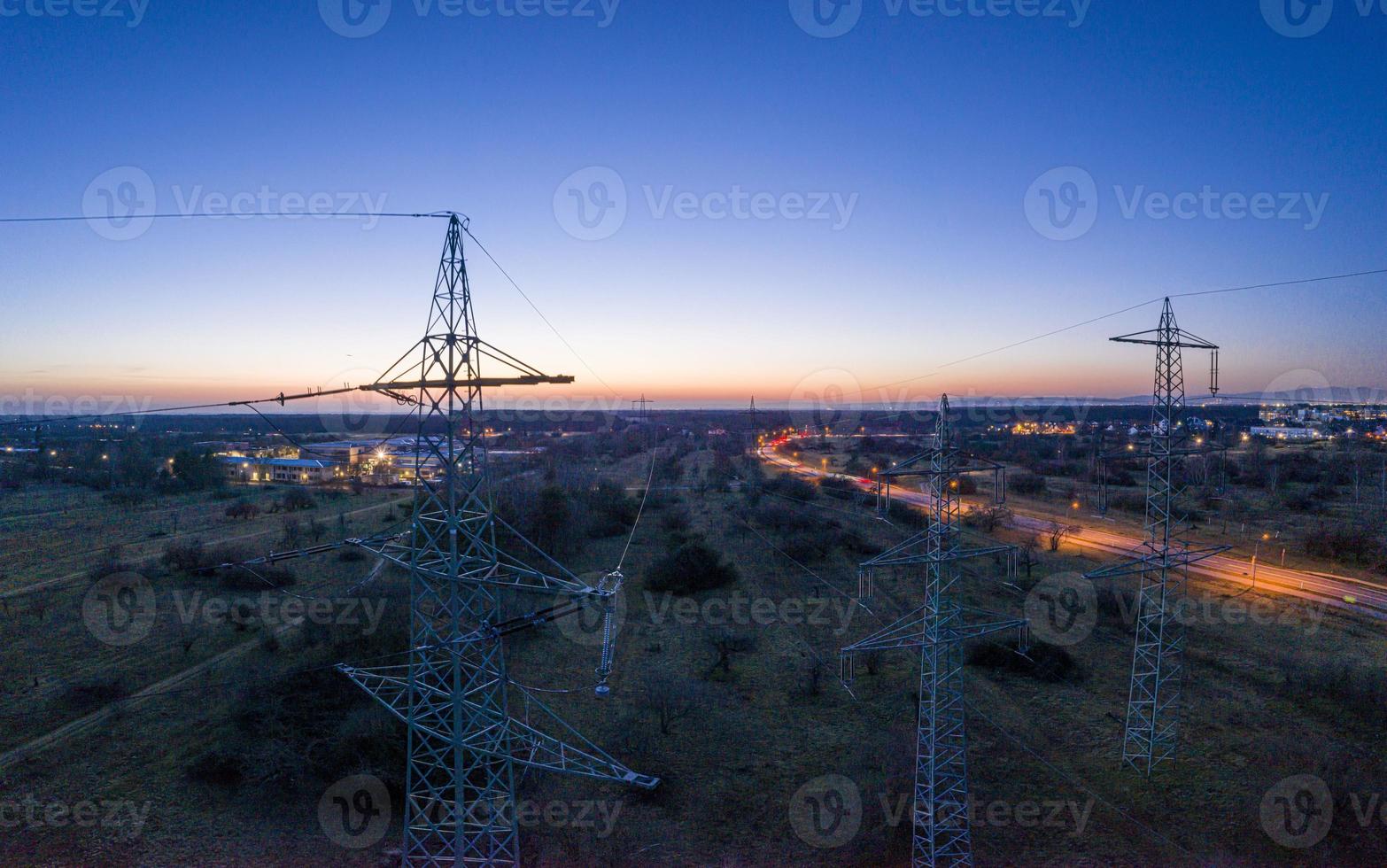 Panoramic image of power pylons against spectacular sunset red at dusk with cloudless sky photo