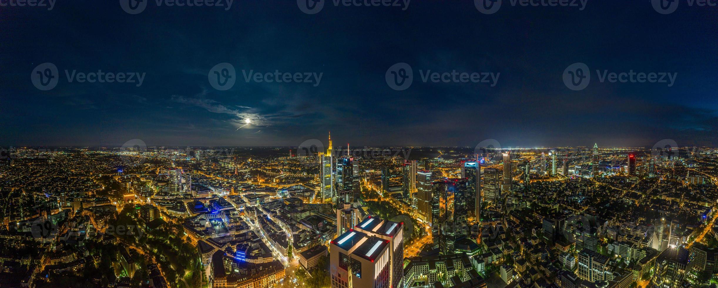 Aerial drone panorama of Frankfurt skyline at night with full moon and illuminated skyscrapers photo