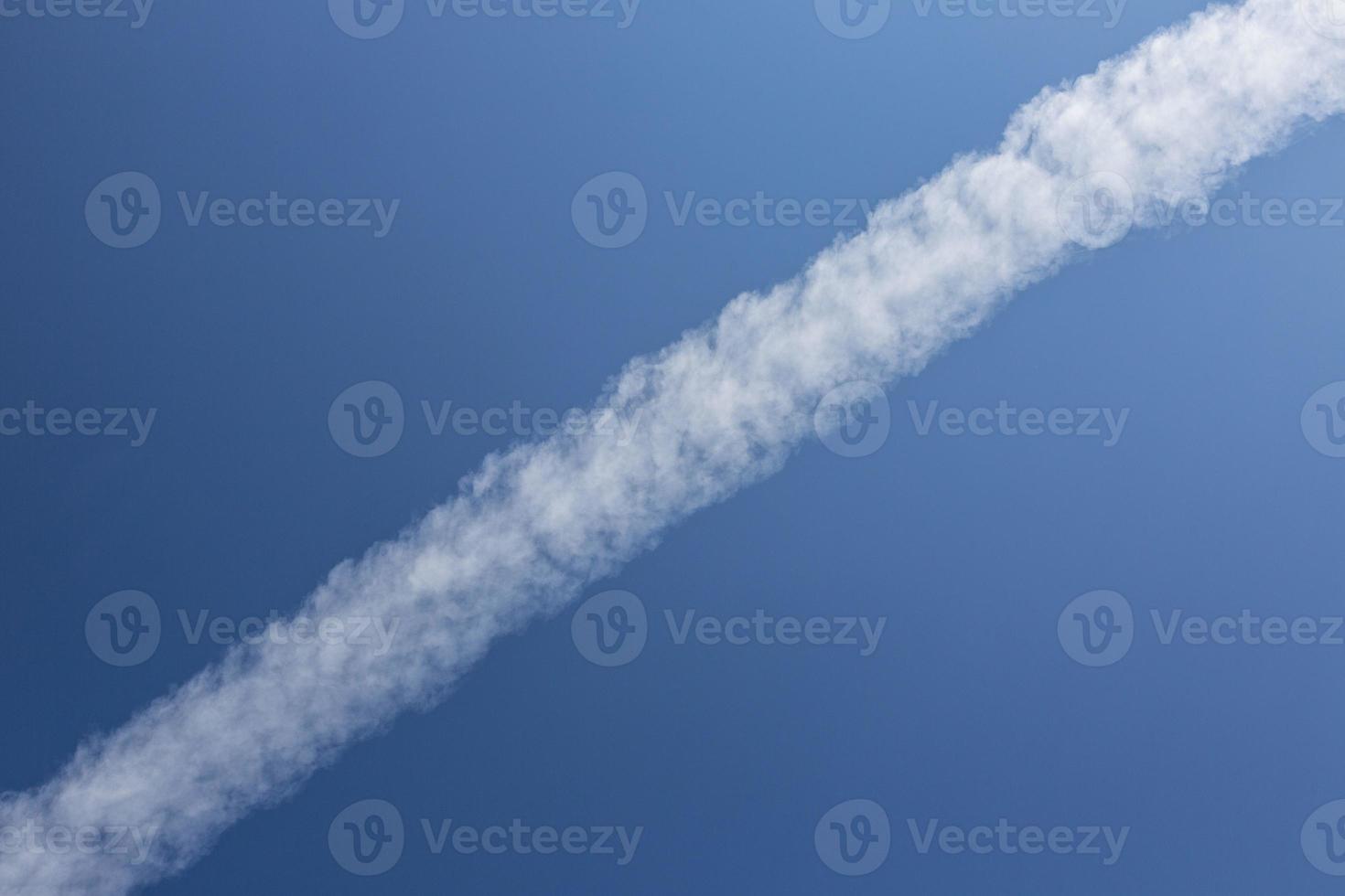 Condensation trail of an airplane in blue sky photo