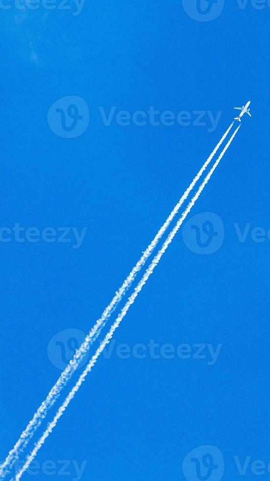 Two engined airplane during flight in high altitude with condensation trails photo