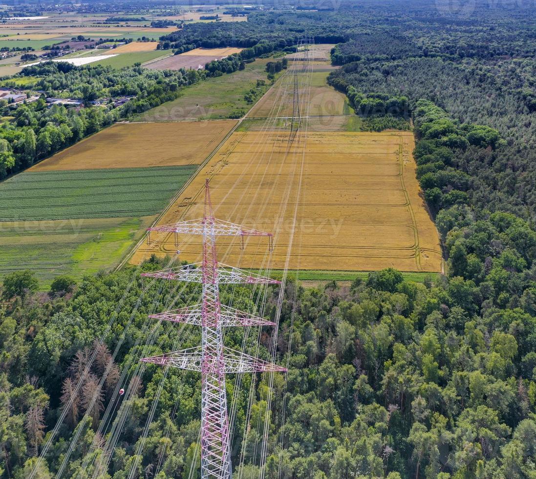 Aerial view along a power line in forest area with metal power poles and high voltage wires photo
