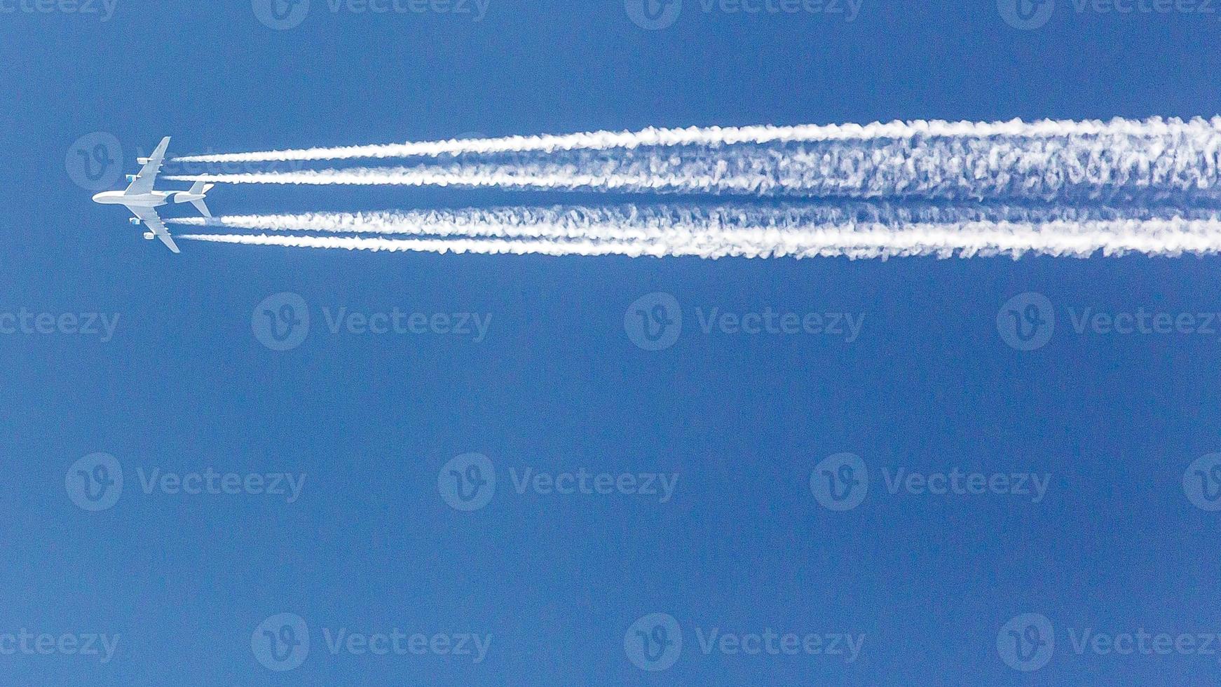 Four engined airplane during flight in high altitude with condensation trails photo