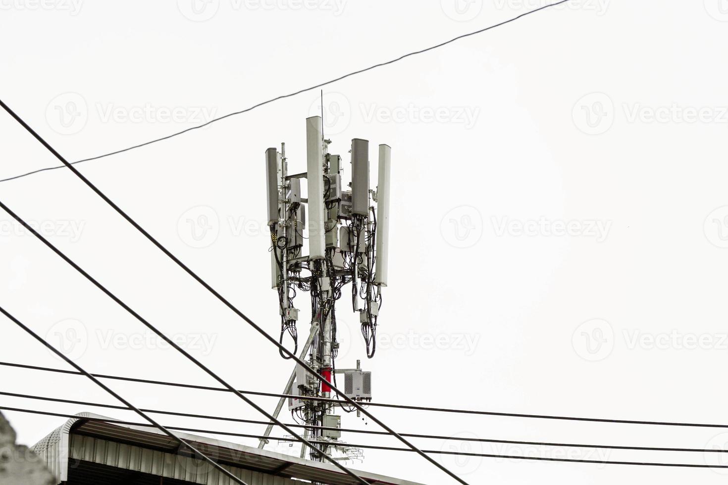 Communication tower with antennas on the top of building and bright blue sky background. photo