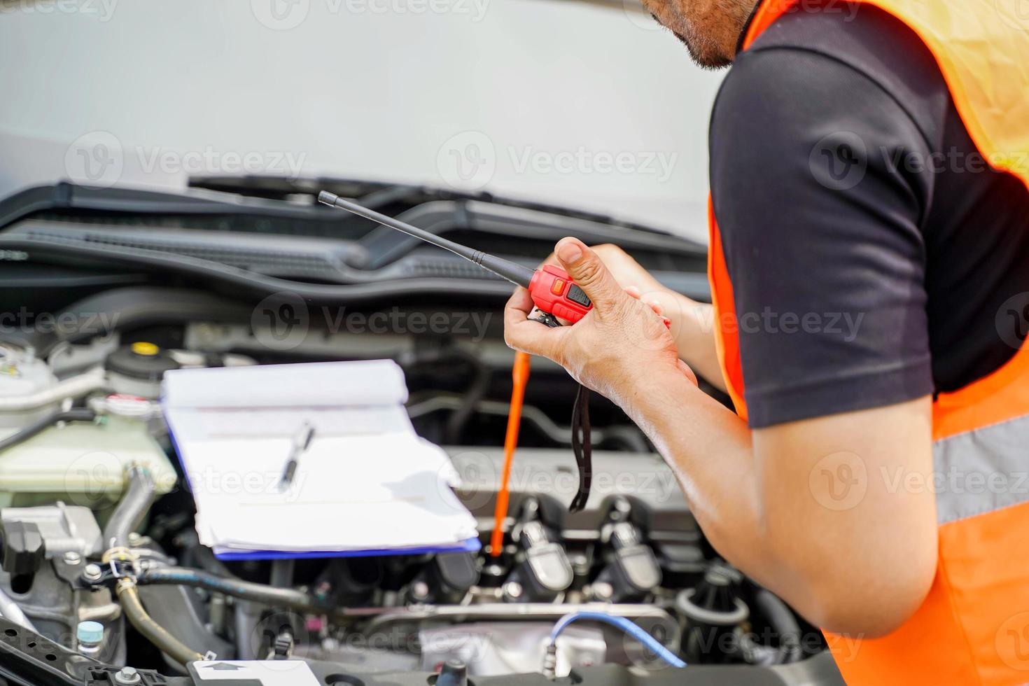 Closeup and crop motor vehicle mechanic checking engine oil to record the repair history with sun and lens flare background. photo