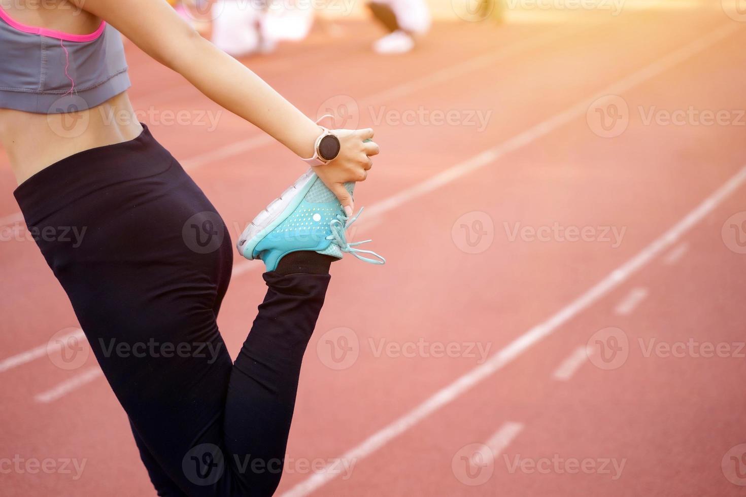 Closeup and crop legs of young female warm up outdoor morning before workout and jogging at the football stadium with sunbeam. photo