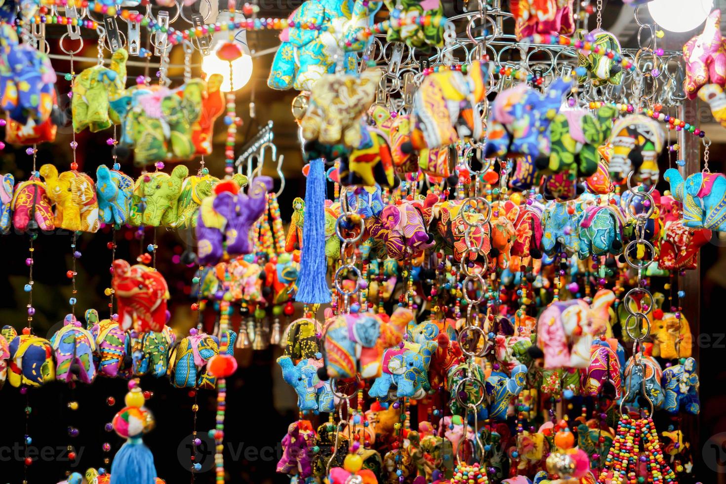 coloridos muñecos de tela de elefante son cortinas y llaveros colgados a la venta en un mercado nocturno. foto