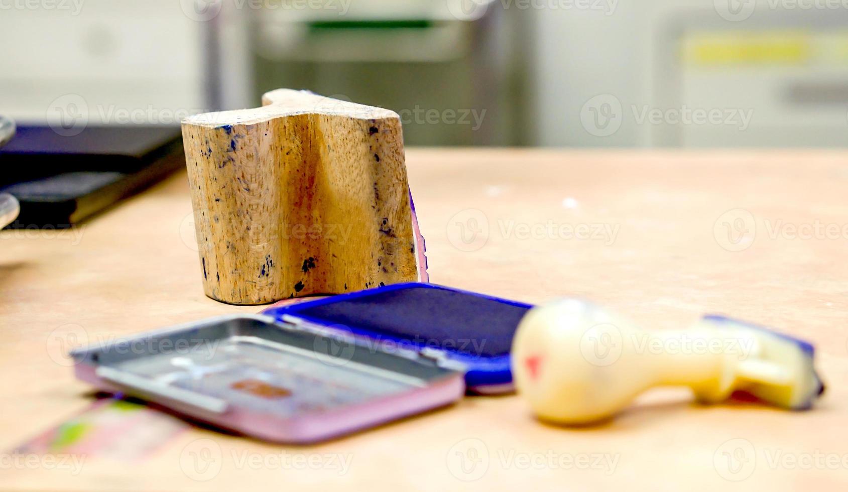 Closeup wooden rubber stamp with blue ink plate on office table and blurry background. photo