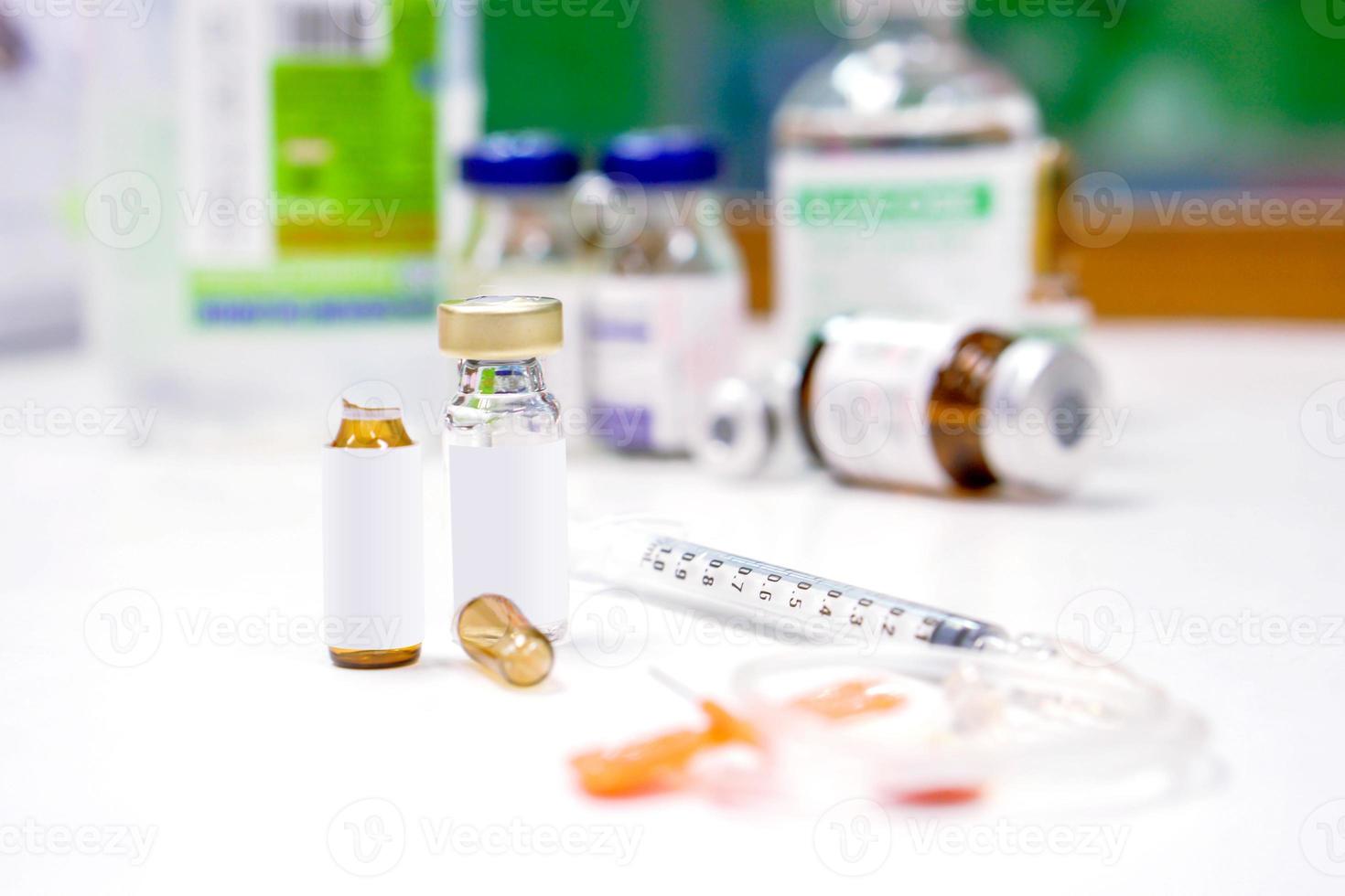 Sample vials and plastic syringe with 3 ml. ampule is opened on white table with ampule blurry background. photo