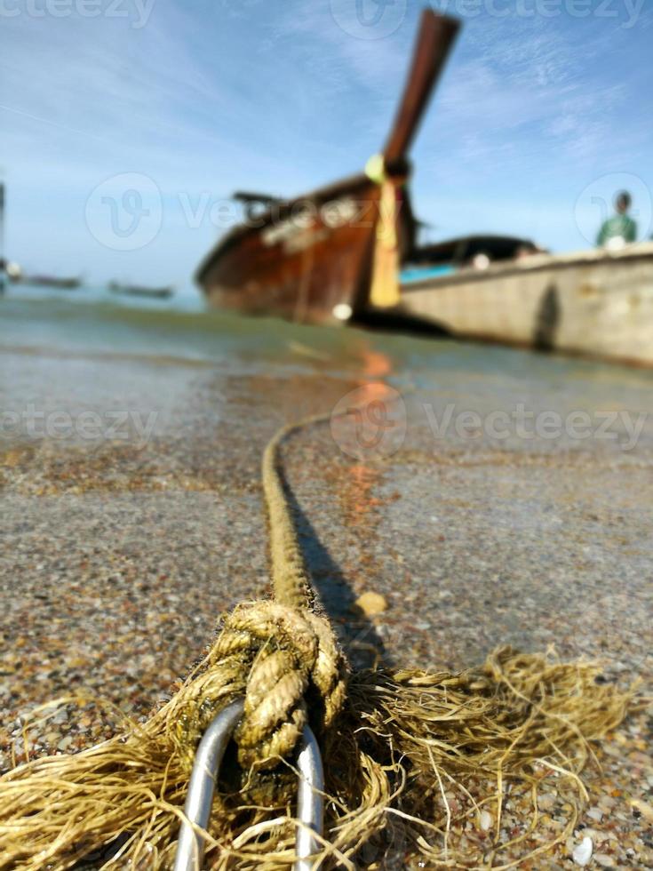 cerca de la cuerda para atar el bote en un bote de cola larga borroso estacionado para esperar a los turistas en la playa de ao nang, tailandia. foto