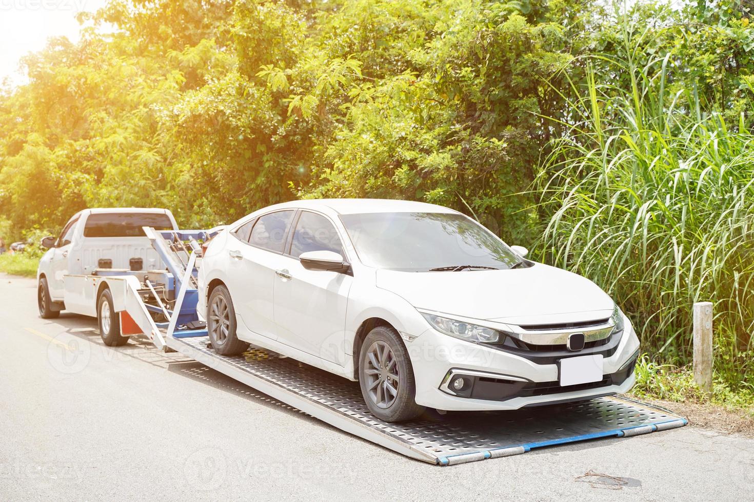 el coche dañado se desliza y el coche blanco en el accidente en la carretera local con el sol y el fondo de las plantas verdes. foto