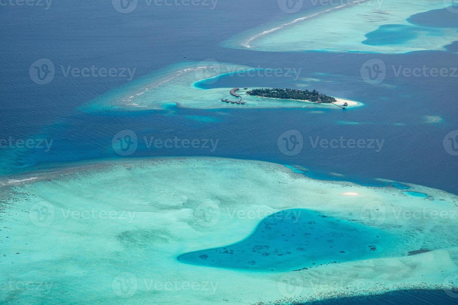 Aerial view of Maldives resort, luxury travel destination. Birds eye view of deep blue sea, coral reed, tropical island. Amazing nature view, drone aerial landscape photo