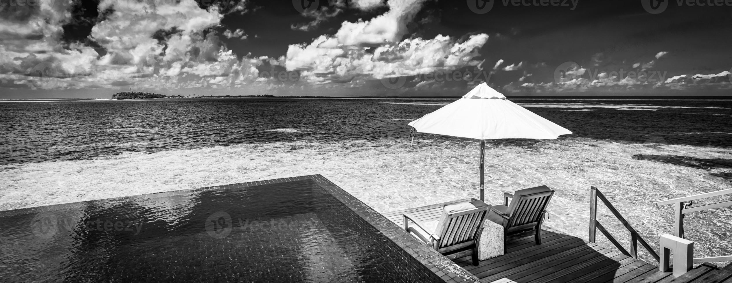 tranquila y lujosa pancarta de playa, vista panorámica de un par de sillas, sombrilla y piscina infinita. resort water villa, maldivas, bora bora. paisaje de playa en blanco y negro, monocromo dramático inspirar cielo mar foto