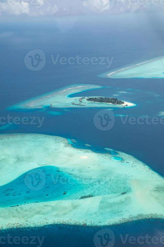 Aerial view of Maldives resort, luxury travel destination. Birds eye view of deep blue sea, coral reed, tropical island. Amazing nature view, drone aerial landscape photo