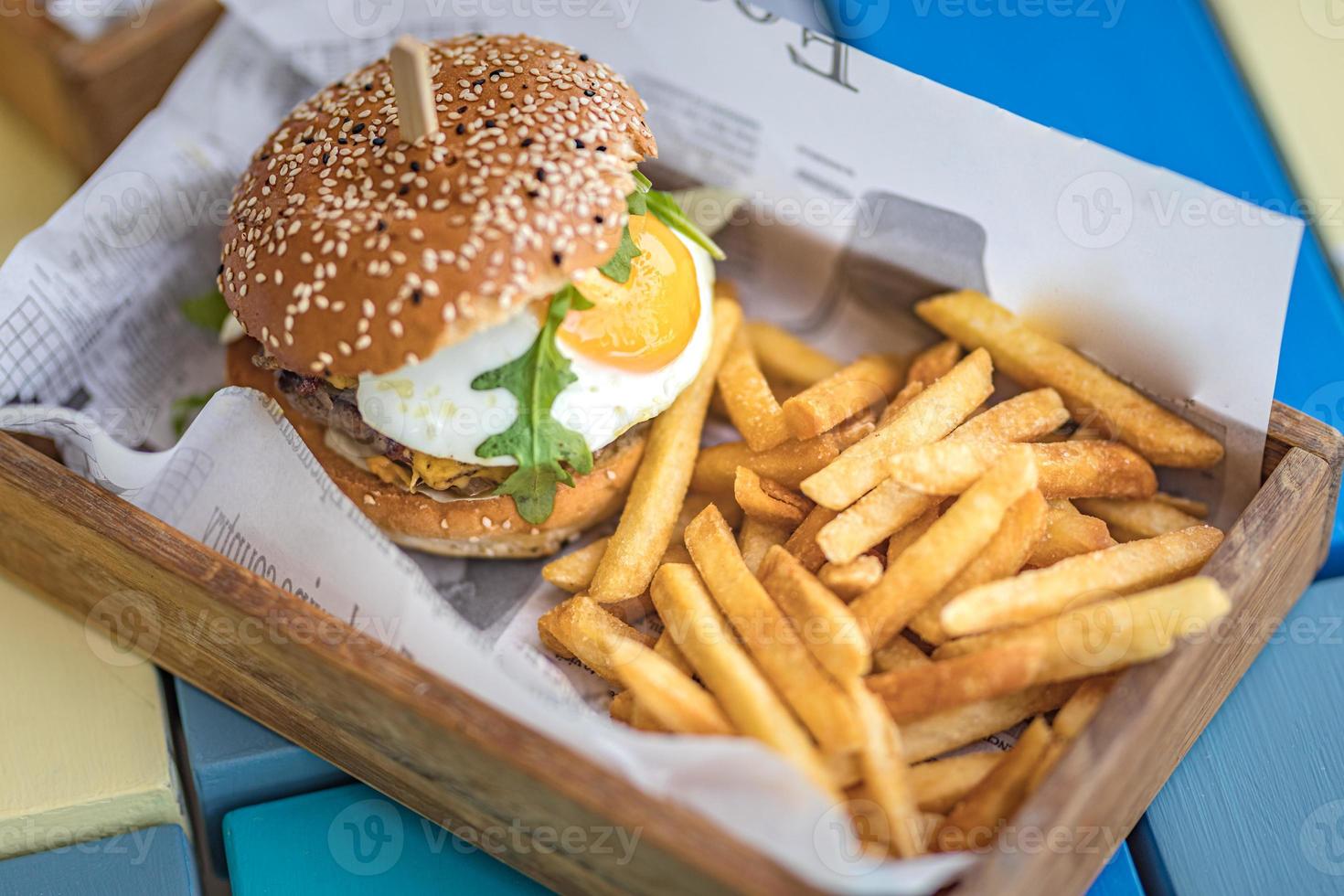 Hamburgers and French fries on the wooden tray. Gourmet beef hamburger with lettuce and cheese fried egg and fries. Delicious lunch photo