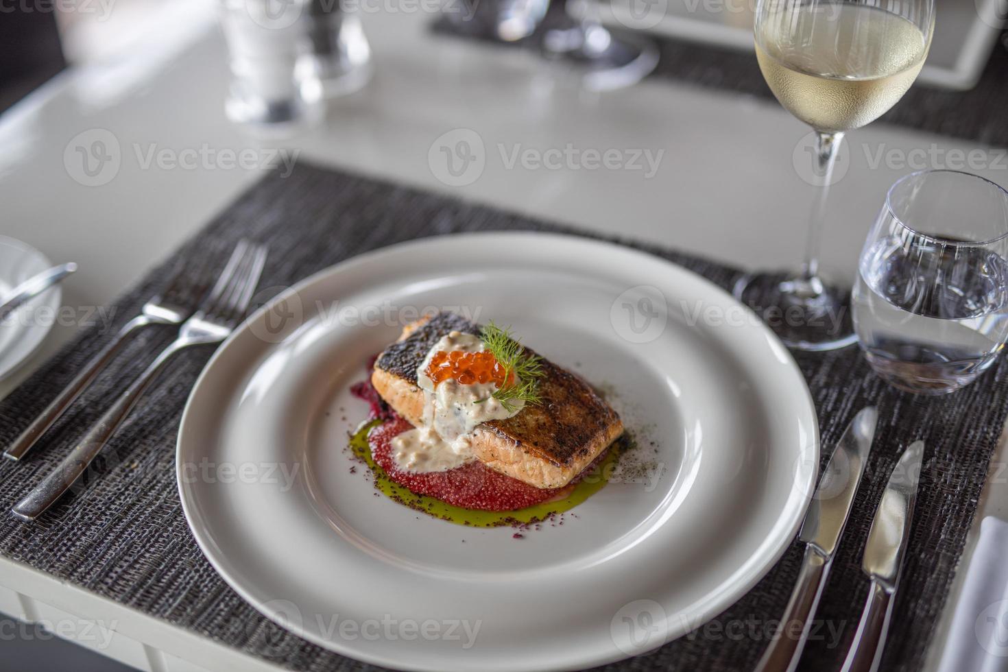Salmon fish elegant gourmet white plate top view lunch or dinner. Gourmet dish meal as fine dining closeup. Caviar seafood on beautiful modern table set-up photo