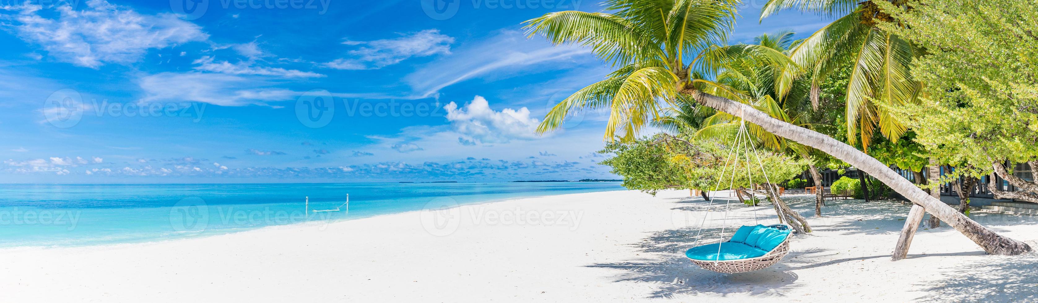 Tropical beach panorama as summer landscape with beach swing or hammock and white sand and calm sea for beach banner. Tranquil beach scene vacation and summer holiday concept. Boost up color process photo