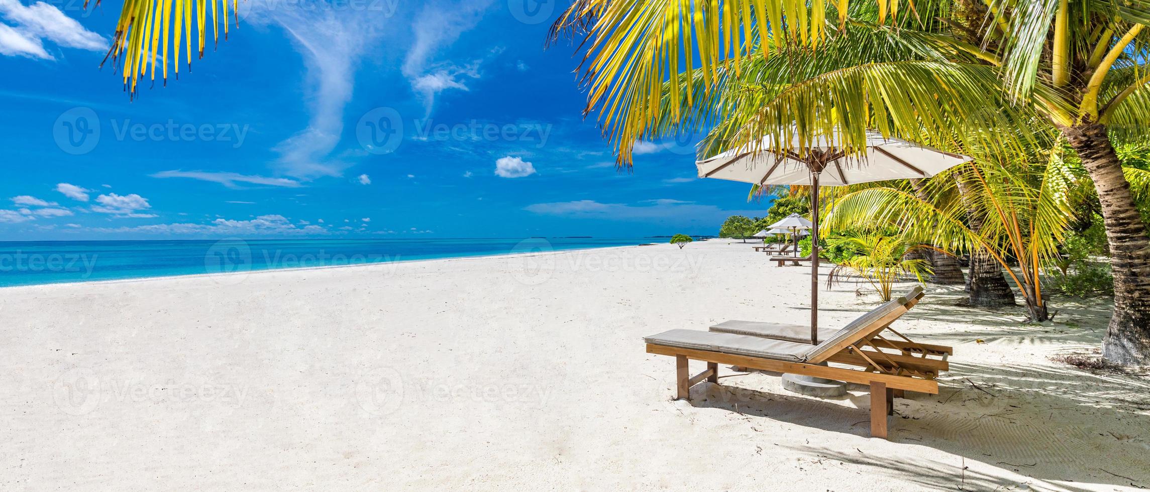 Beautiful panoramic beach. Chairs on the sandy beach near the sea with palm leaves. Perfect summer vibes for holiday and vacation concept as luxury travel background. Inspirational tropical landscape photo