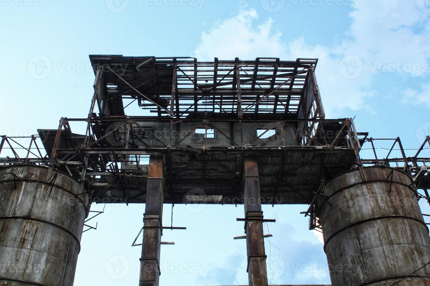 Rusty structures pipes of an old abandoned destroyed industrial steel factory. The overgrown ruins of complex building area. The concept of bankruptcy, and the closure of production and jobs photo