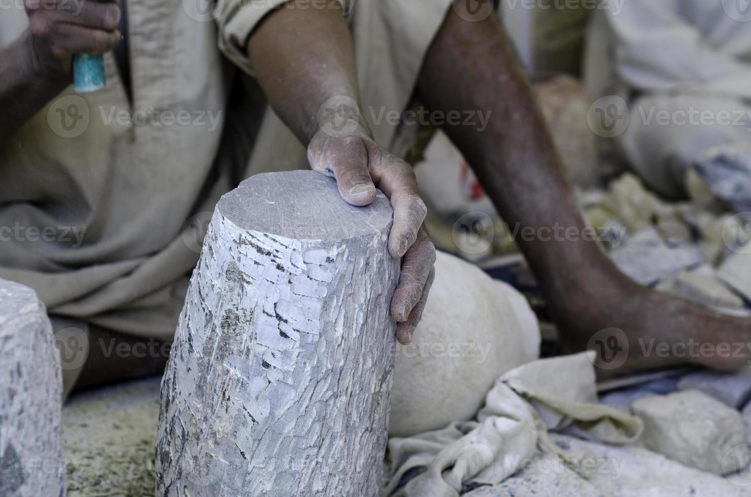 Manos de un escultor egipcio mientras trabajaba con un alabastro de piedra foto