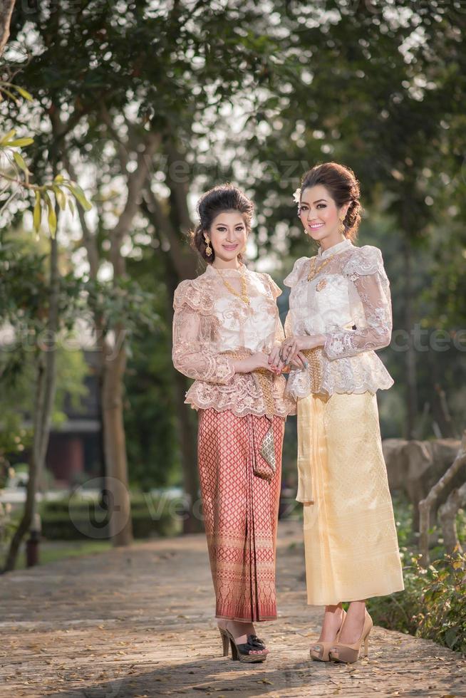 Two beautiful girls getting dressed in Thai Traditional Costume photo